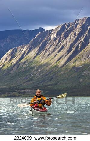 Kayaker on Kusawa Lake with the setting sun hitting the mountains; Yukon, Canada View Large Photo Image Stock Photo - Kayaker on Kusawa Lake with the setting sun hitting the mountains; Yukon, Canada. Fotosearch