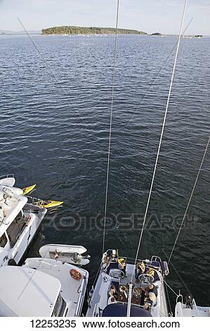 Stock Photography - Kayakers pass a flotilla of power boats and sailboats just off of Sidney Island; Sidney, British Columbia, Canada. Fotosearch