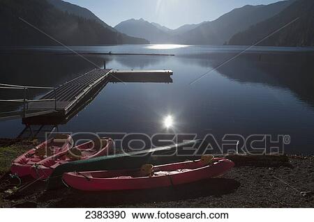 Stock Image - Kayaks on the shore of tranquil Lake Crescent at sunrise, Olympic National Park; Washington, United States of America. Fotosearch