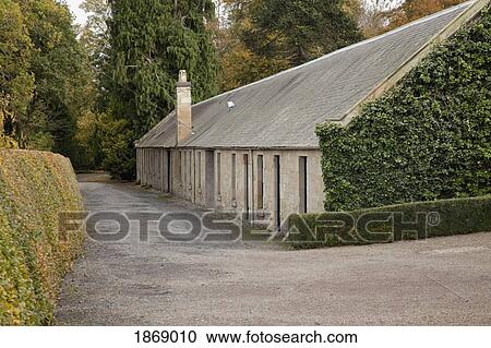 Stock Image - Kelso, Scottish Borders, Scotland; The Exterior Of A Stone Building Surrounded By Hedges. Fotosearch
