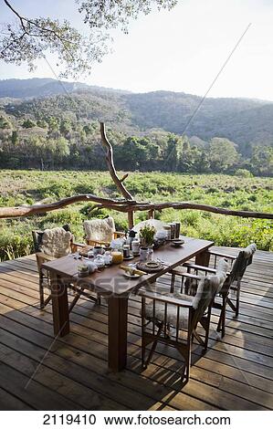 Stock Image - Kenya, Breakfast table set up on porch at Kitich camp; Mathews Mountain Range. Fotosearch