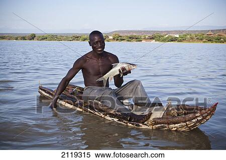 Stock Photography - Kenya, Rift Valley, Fisherman showing fish in small canoe; Lake Baringo. Fotosearch