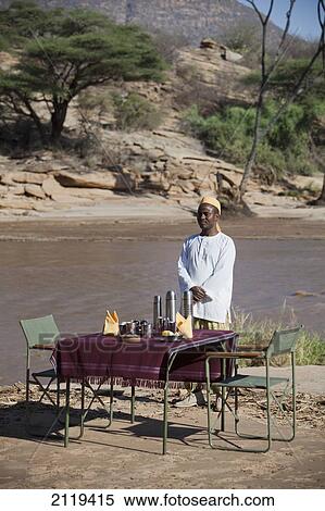 Stock Photography - Kenya, Riverside breakfast table set up for guests at Joy's Camp; Shaba National Reserve. Fotosearch