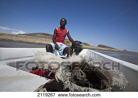Stock Photo - Kenya, Turkana, Man sitting in fishing boat in Central Island National Park; Turkana Lake. Fotosearch