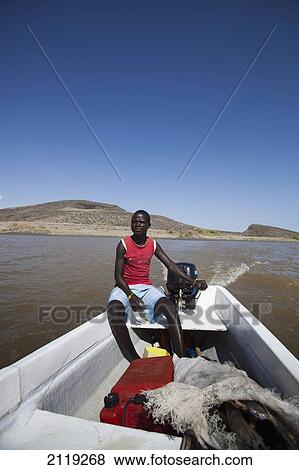 Stock Photo - Kenya, Turkana, Man sitting in fishing boat in Central Island National Park; Turkana Lake. Fotosearch