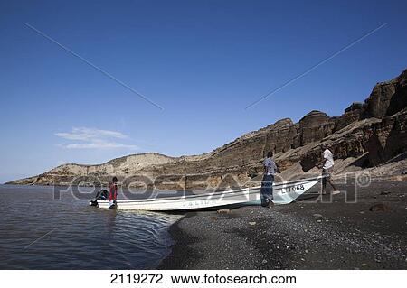 Stock Image - Kenya, Turkana, View of men and fishing boat in Central Island National Park; Turkana Lake. Fotosearch