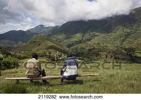 Stock Image - Kenya, Two men sitting on bench in Cherangani hills; Western Highlands. Fotosearch