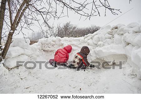 Stock Image - Kids building a snow fort; Ontario, Canada. Fotosearch