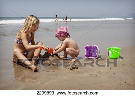 Stock Image - Kids play together on holiday making sandcastles, Turtle Beach, Goa, India.. Fotosearch