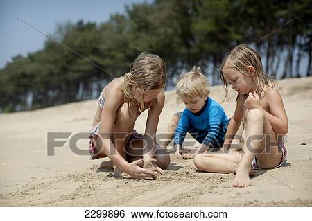 Stock Photograph - Kids play together on holiday making sandcastles, Turtle Beach, Goa, India.. Fotosearch