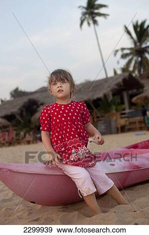 Stock Photo - Kiki Lett aged 5 sits on a canoe, Patnum Beach, Goa, India.. Fotosearch