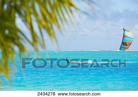Stock Photo - Kiteboarding in the lagoon over tropical blue water; Bora Bora, French Polynesia. Fotosearch