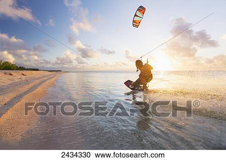 Stock Image - Kiteboarding in tropical lagoon in the South Pacific at sunset; Tikehau, French Polynesia. Fotosearch