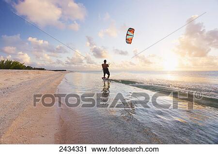 Stock Image - Kiteboarding in tropical lagoon in the South Pacific at sunset; Tikehau, French Polynesia. Fotosearch