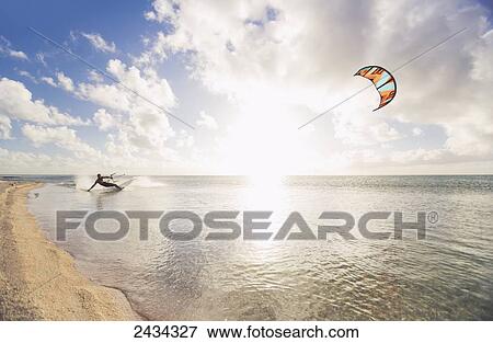 Stock Photo - Kiteboarding in tropical lagoon in the South Pacific at sunset; Tikehau, French Polynesia. Fotosearch