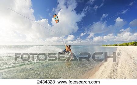 Stock Photo - Kiteboarding in tropical lagoon in the South Pacific at sunset; Tikehau, French Polynesia. Fotosearch