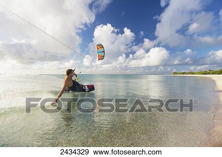 Stock Photo - Kiteboarding in tropical lagoon in the South Pacific at sunset; Tikehau, French Polynesia. Fotosearch