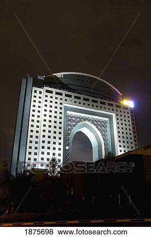 Stock Photo - Kuala Lumpur, Malaysia; A Building With An Archway Through It Illuminated At Night. Fotosearch