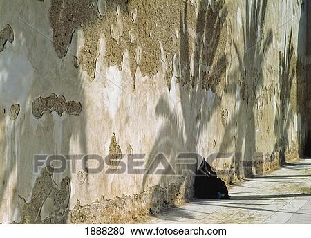 Stock Image - Lady Wearing Djelleba Sitting In Shade By Wall. Fotosearch