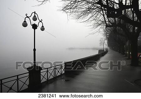 Lamp post and trees on a promenade along Lake Maggiore; Locarno, Ticino, Switzerland View Large Photo Image Stock Image - Lamp post and trees on a promenade along Lake Maggiore; Locarno, Ticino, Switzerland. Fotosearch