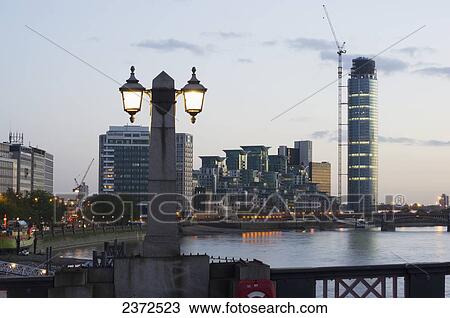 Lamp post illuminated at dusk and buildings along the waterfront; London, England View Large Photo Image Stock Image - Lamp post illuminated at dusk and buildings along the waterfront; London, England. Fotosearch