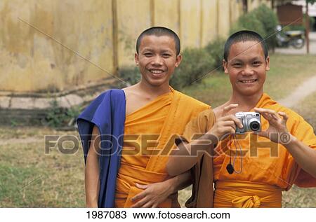 Stock Image - Laos, Vientiane, Si Saket Temple, Two Young Monks In Front Of Building, Enjoying Camera.. Fotosearch