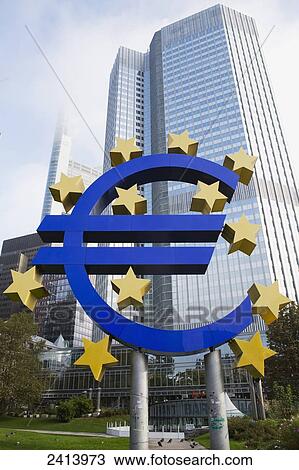 Stock Image - Large Euro monument against the background of large skyscrapers; Frankfurt am Main, Germany. Fotosearch