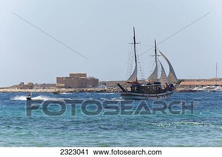 Stock Image - Large ship sailing in harbor and a rider on a personal watercraft; Paphos, Cyprus. Fotosearch
