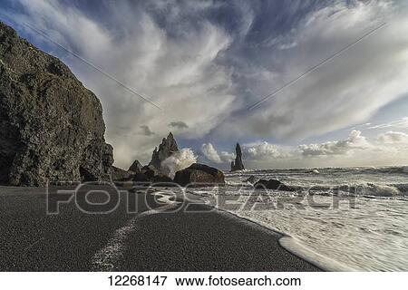Stock Photo - Large waves crash against the shoreline and sea stacks on the southern shore of Iceland, near Vik; Iceland. Fotosearch