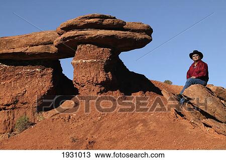 Stock Image - Larry Holiday, Navajo guide, sitting near a rock formation in Monument Valley Navajo Park. Utah, Arizona., Utah, Arizona.. Fotosearch