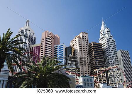 Stock Image - Las Vegas, Nevada, United States Of America; Building Facades Of New York, New York With Roller Coaster And Palm Trees. Fotosearch
