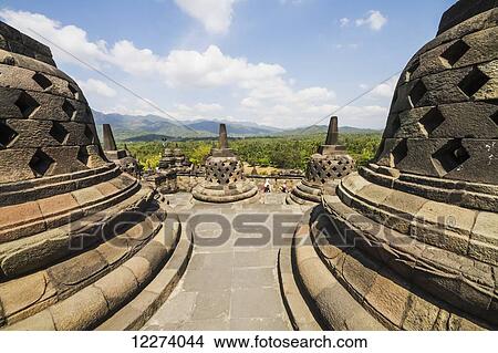Picture - Latticed stone stupas containing Buddha statues on the upper terrace, Borobudur Temple Compounds, Central Java, Indonesia. Fotosearch