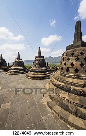 Stock Image - Latticed stone stupas containing Buddha statues on the upper terrace, Borobudur Temple Compounds, Central Java, Indonesia. Fotosearch