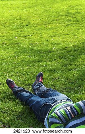 Stock Image - Laying down on the lush green grass, Hamstead Heath; London, England. Fotosearch