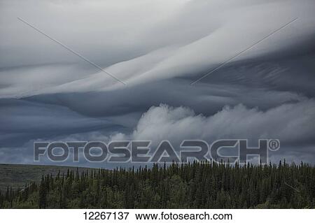 Stock Photo - Lenticular clouds form over the flanks of Crow Mountain; Old Crow, Yukon, Canada. Fotosearch