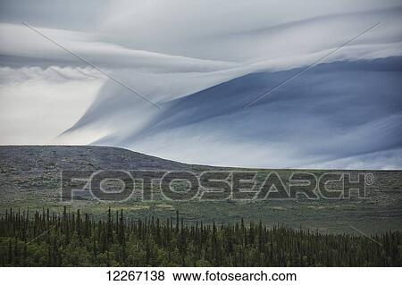 Stock Photo - Lenticular clouds form over the flanks of Crow Mountain; Old Crow, Yukon, Canada. Fotosearch