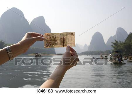 Stock Photo - Li River, Yangshuo, China; Person Holding Up Chinese Currency. Fotosearch