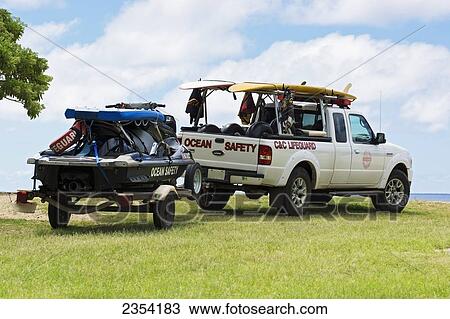 Stock Image - Lifeguard safety vehicles parked by the shore of Waimea Bay; Oahu, Hawaii, United States of America. Fotosearch