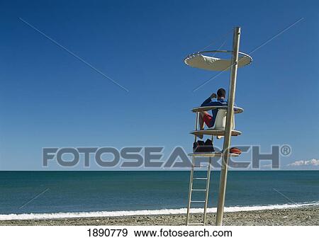 Lifeguard Sitting At Tower On Beach View Large Photo Image Stock Photo - Lifeguard Sitting At Tower On Beach. Fotosearch