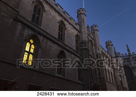 Stock Image - Light coming from a window on building on The Old Schools Site at dusk; Cambridge, Cambridgeshire, England. Fotosearch