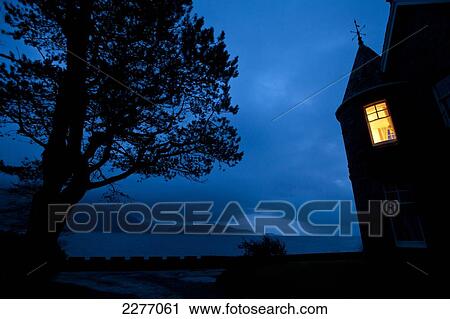 Stock Image - Light in turret of house at dusk; Onich, Highlands, Scotland. Fotosearch
