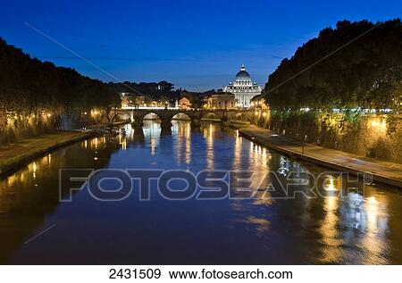 Light reflected in the tranquil river water with a bridge and illuminated buildings in the distance; Rome, Italy View Large Photo Image Stock Photo - Light reflected in the tranquil river water with a bridge and illuminated buildings in the distance; Rome, Italy. Fotosearch