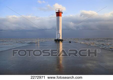 Stock Image - Lighthouse reflected on a wet pier on a stormy day by lake ontario; whitby ontario canada. Fotosearch