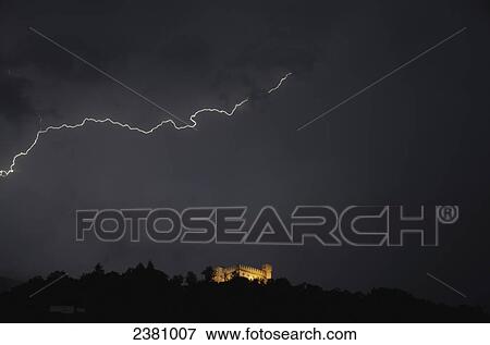 Stock Photo - Lightning strike in the dark sky and an illuminated castle below; Bellinzona, Ticino, Switzerland. Fotosearch
