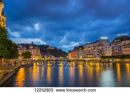 Stock Image - Lights and buildings reflected on River Reuss at nighttime; Lucerne, Switzerland. Fotosearch