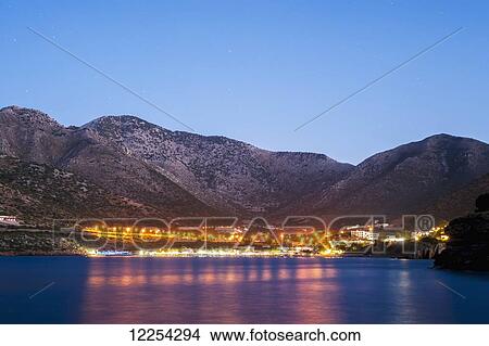 Picture - Lights illuminate the city and reflect on the water; Bali, Crete, Greece. Fotosearch