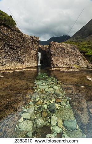 Stock Image - Line of pale rocks leading to waterfall in Coire na Creiche (The Fairy Pools) near Glen Brittle; Isle of Skye, Scotland. Fotosearch