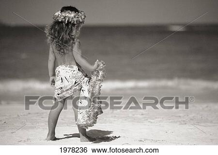 Stock Photograph - Little Girl At The Beach, Holding Lei And Wearing A Pareo, View From Behind (Sepia Photograph).. Fotosearch