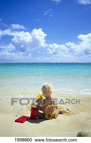 Stock Image - Little Girl Plays With Sand On Shore Of Turquoise Ocean B1014. Fotosearch