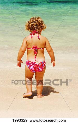 Stock Photo - Little Girl With Blond Curly Hair Plays On The Beach. Fotosearch